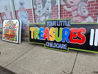 Your Little Treasures Childcare sign panel leaning against a wall outdoors