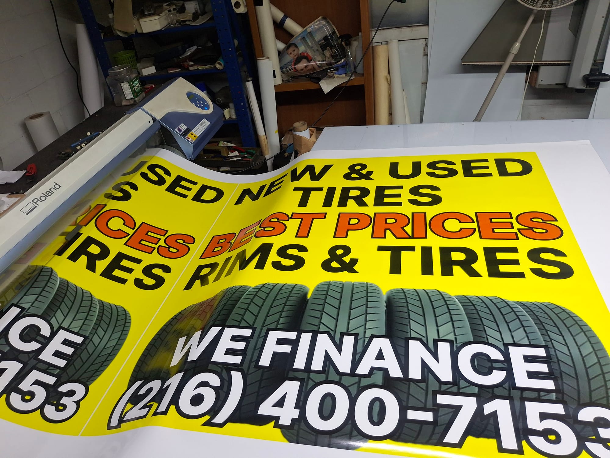 Printed yellow New & Used Tires banners with a phone number on the shop table