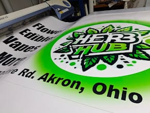Printed Herb Hub banner with an Akron, Ohio address feeding out of a printer