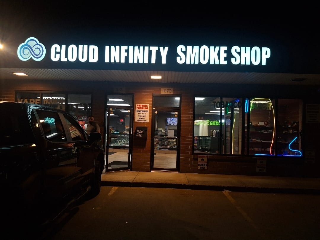 Illuminated Cloud Infinity Smoke Shop channel letters above a storefront at night