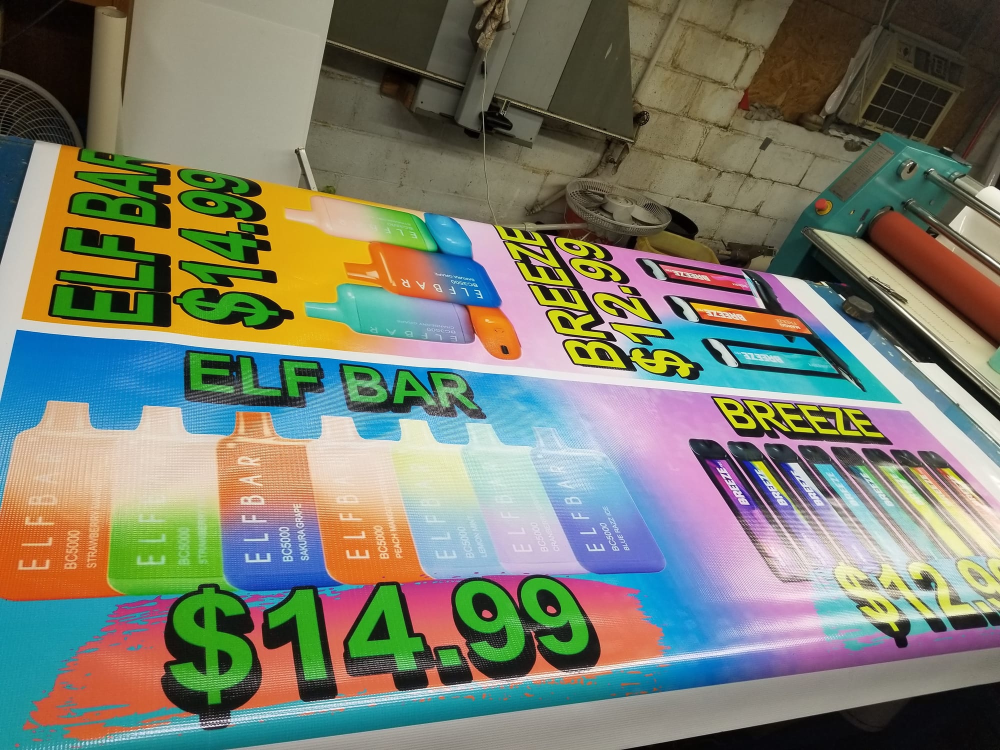 Printed Elf Bar and Breeze price banners laid out in the shop