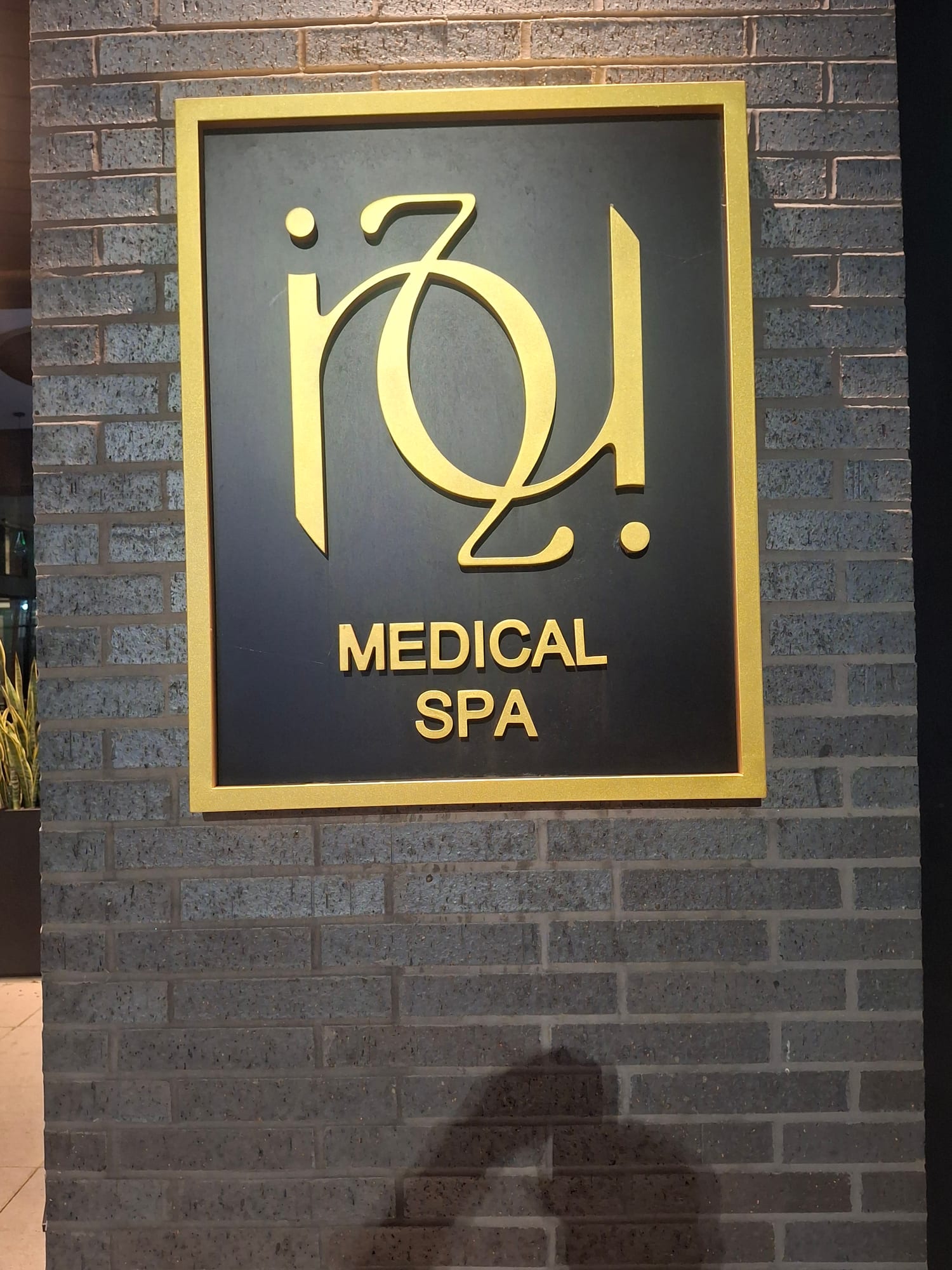 Gold dimensional MEDICAL SPA lettering on a dark framed panel mounted to brick