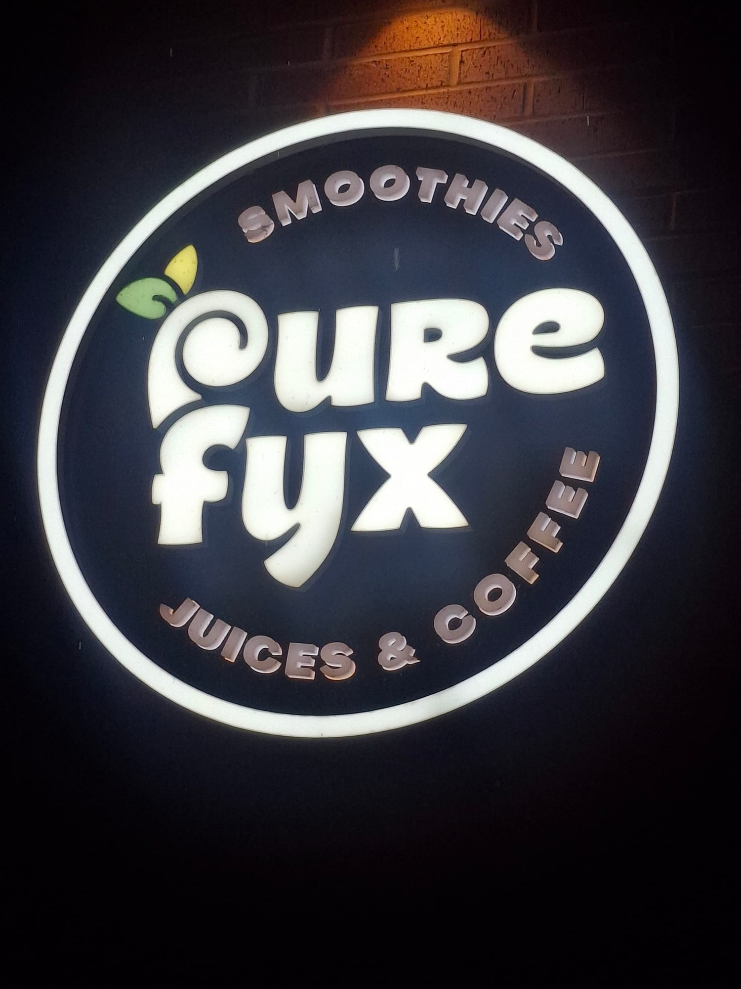 Illuminated round pure fyx smoothies, juices and coffee cabinet sign at night