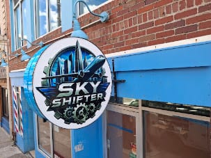 Round Sky Shifter projecting blade sign mounted on a brick storefront