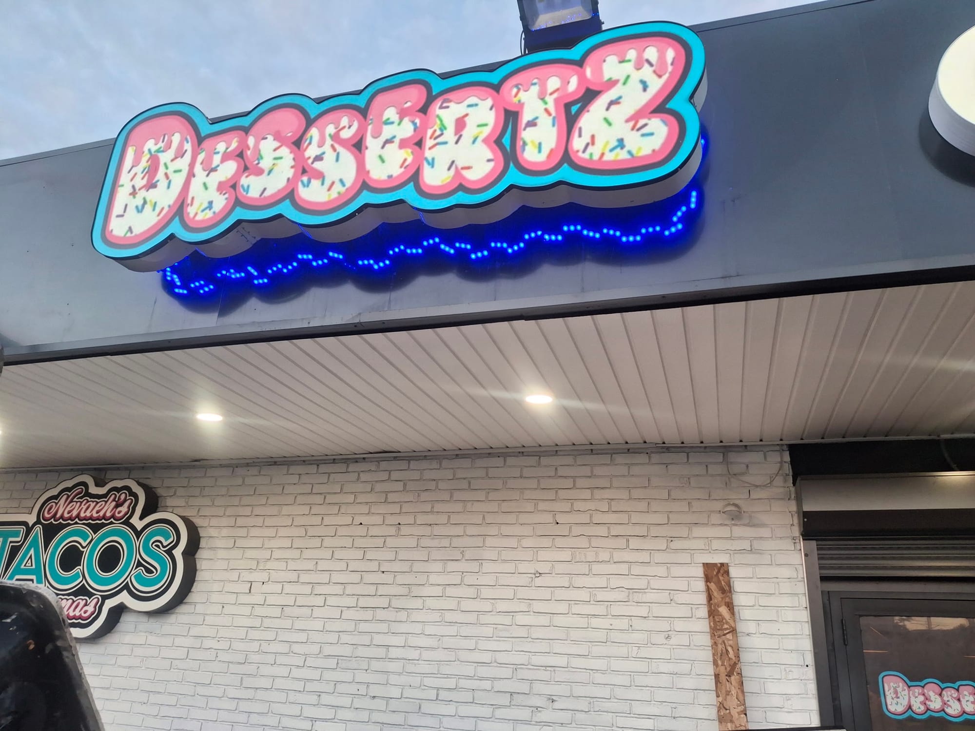 Illuminated Dessertz shaped sign with blue LED trim above a storefront entrance