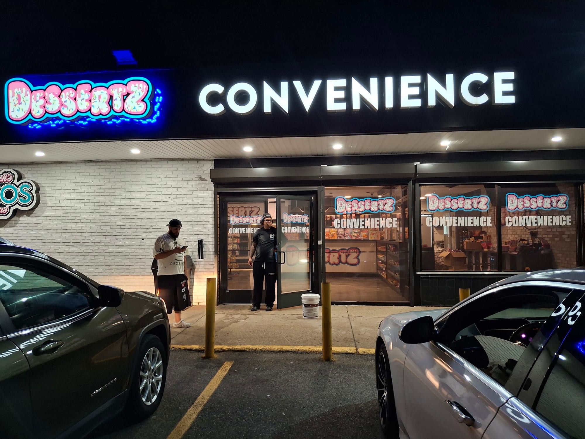 Lit CONVENIENCE channel letters and Dessertz sign over the storefront at night