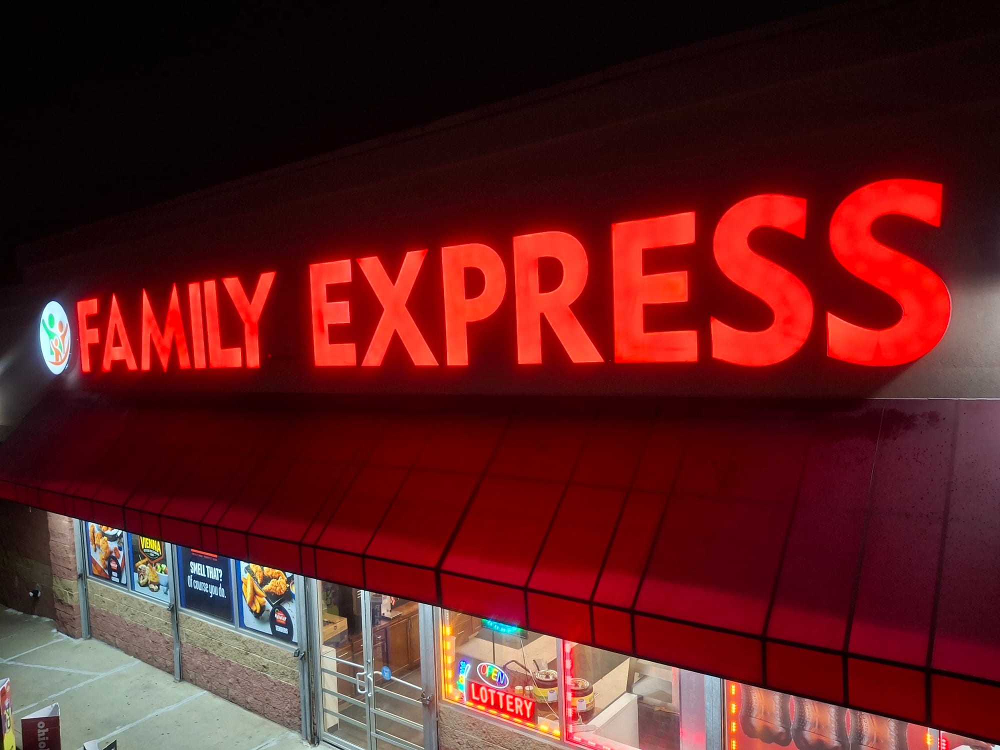 Red illuminated FAMILY EXPRESS channel letters above a storefront awning at night