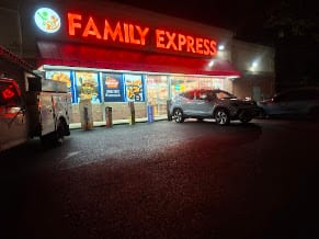Distant night view of the lit Family Express storefront sign