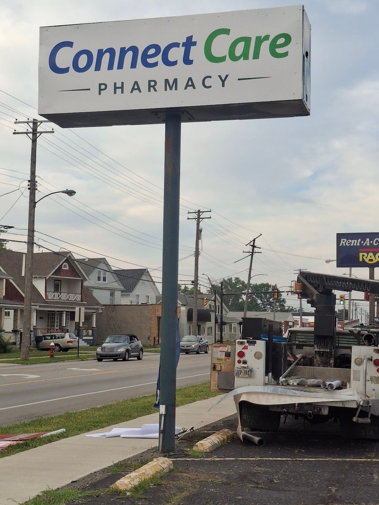 Connect Care Pharmacy pole sign cabinet installed roadside with a bucket truck nearby