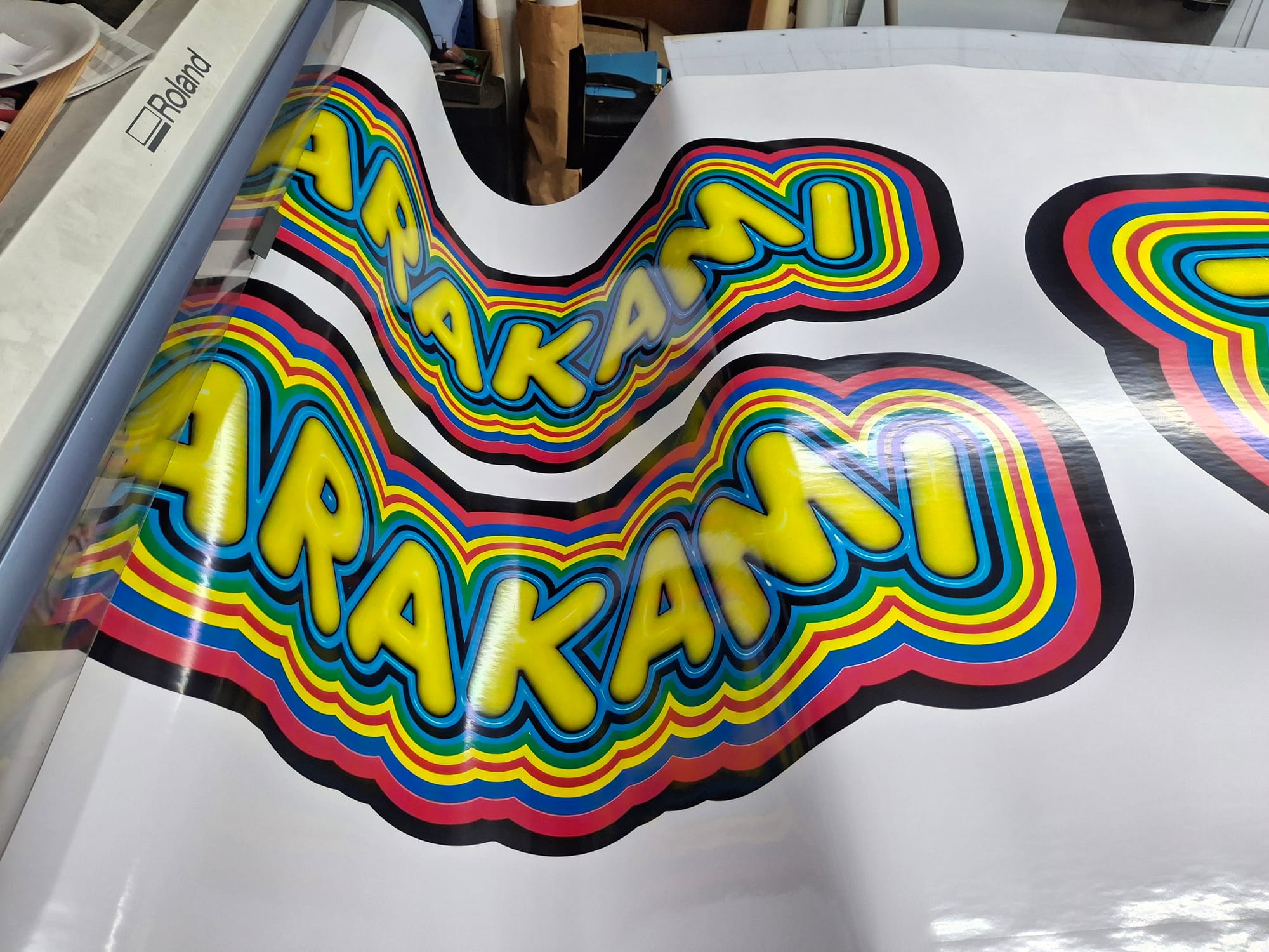 Freshly printed multicolor vinyl lettering decals coming off a Roland wide-format printer