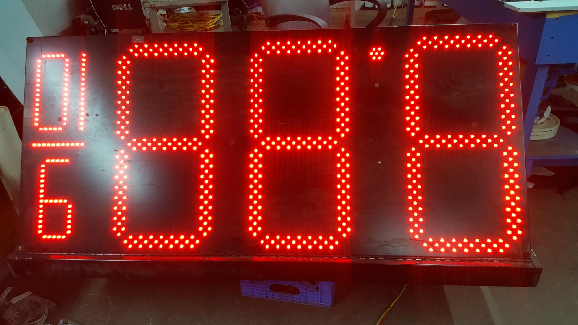 Red LED digit price display panel lit up on a workbench in the sign shop