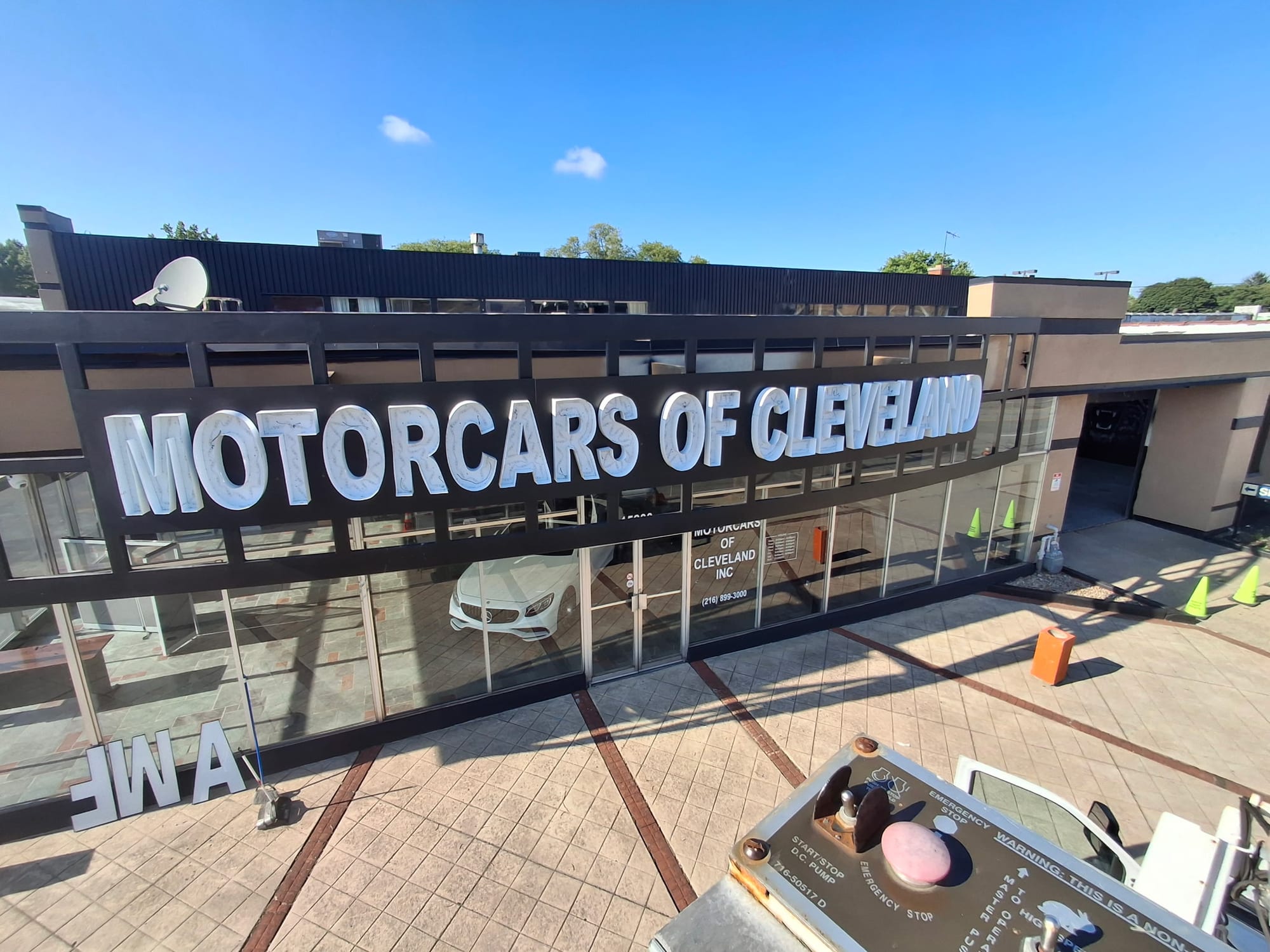 View from a lift basket of mounted MOTORCARS OF CLEVELAND letters with spares on the ground