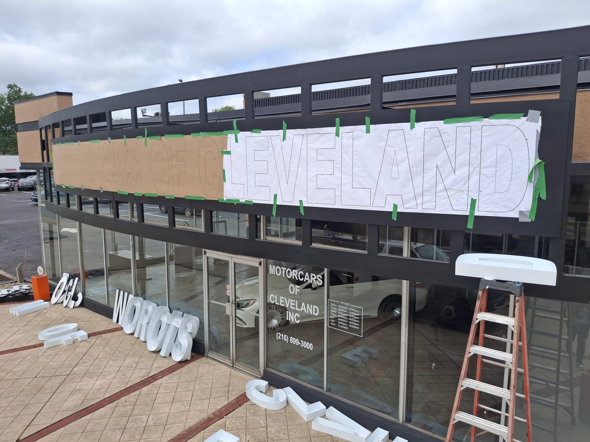 Paper layout template taped to a fascia with channel letters waiting on the sidewalk