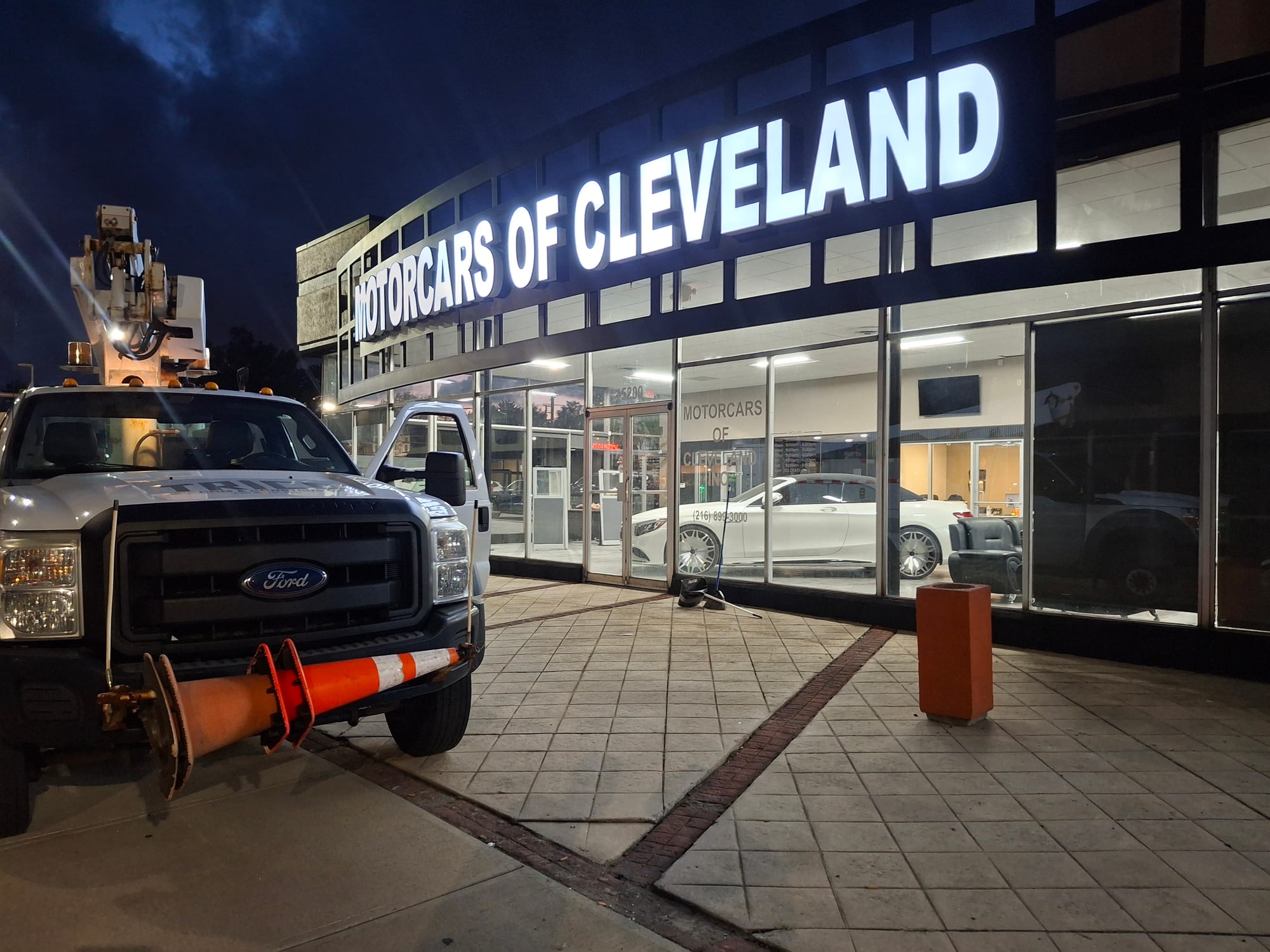 MOTORCARS OF CLEVELAND channel letters lit at night above the dealership storefront