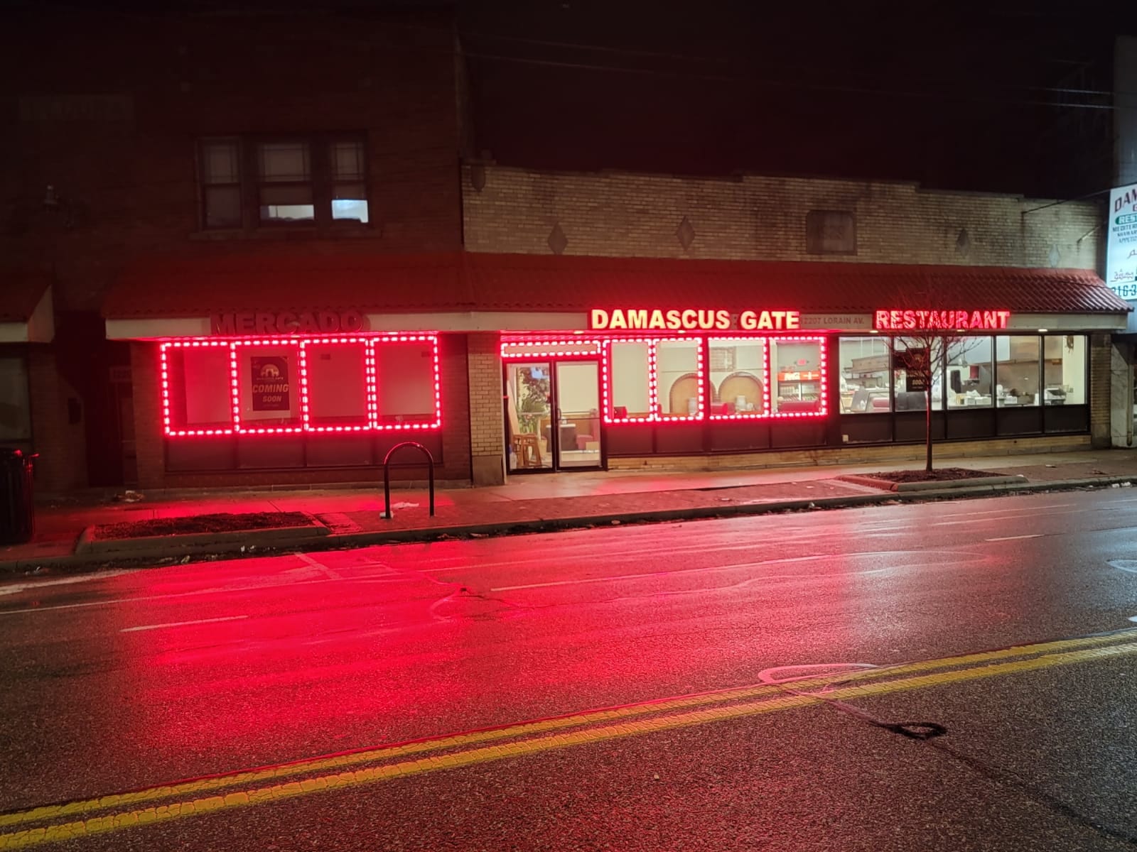 Lit DAMASCUS GATE RESTAURANT letters and red LED window outlines on a storefront at night