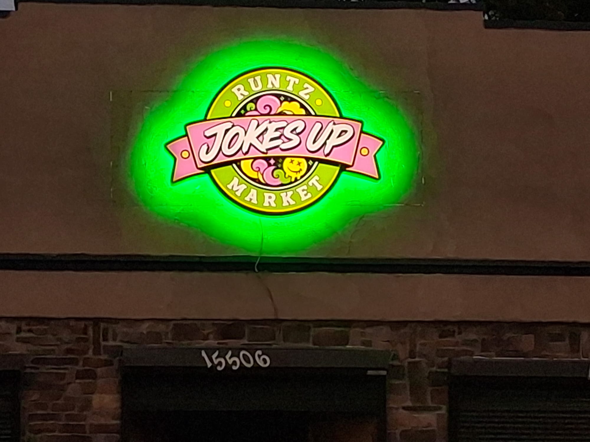Jokes Up Runtz Market logo cabinet sign glowing with a green halo at night