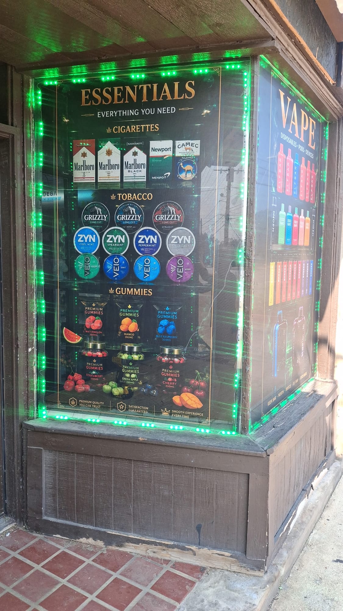 ESSENTIALS printed window graphic with green LED border beside a VAPE panel