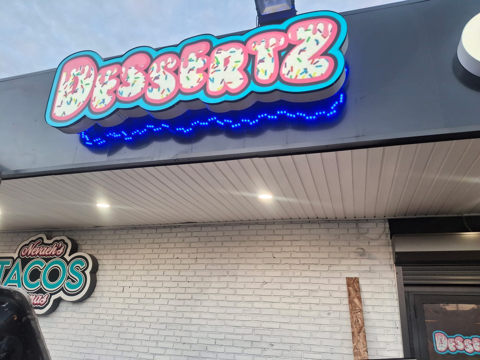 Illuminated DESSERTZ sign with blue LED accent above a storefront entrance