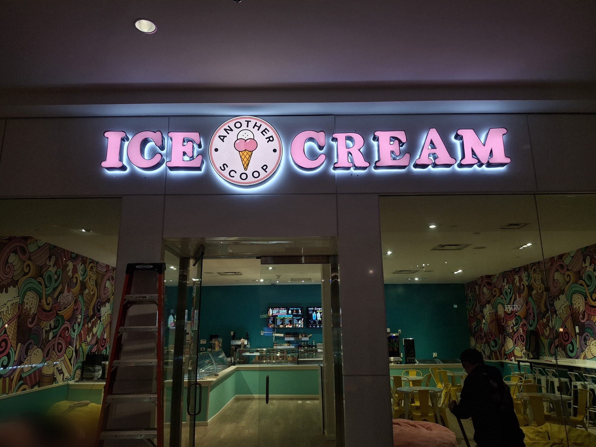 Straight-on night view of the completed Another Scoop sign above the shop entrance